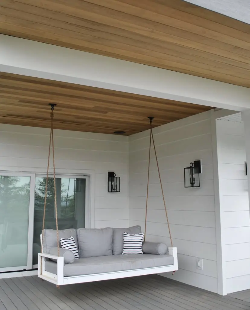 The interior of the home, showcasing a cozy seating area with a hanging swing chair suspended from the wooden ceiling beams.