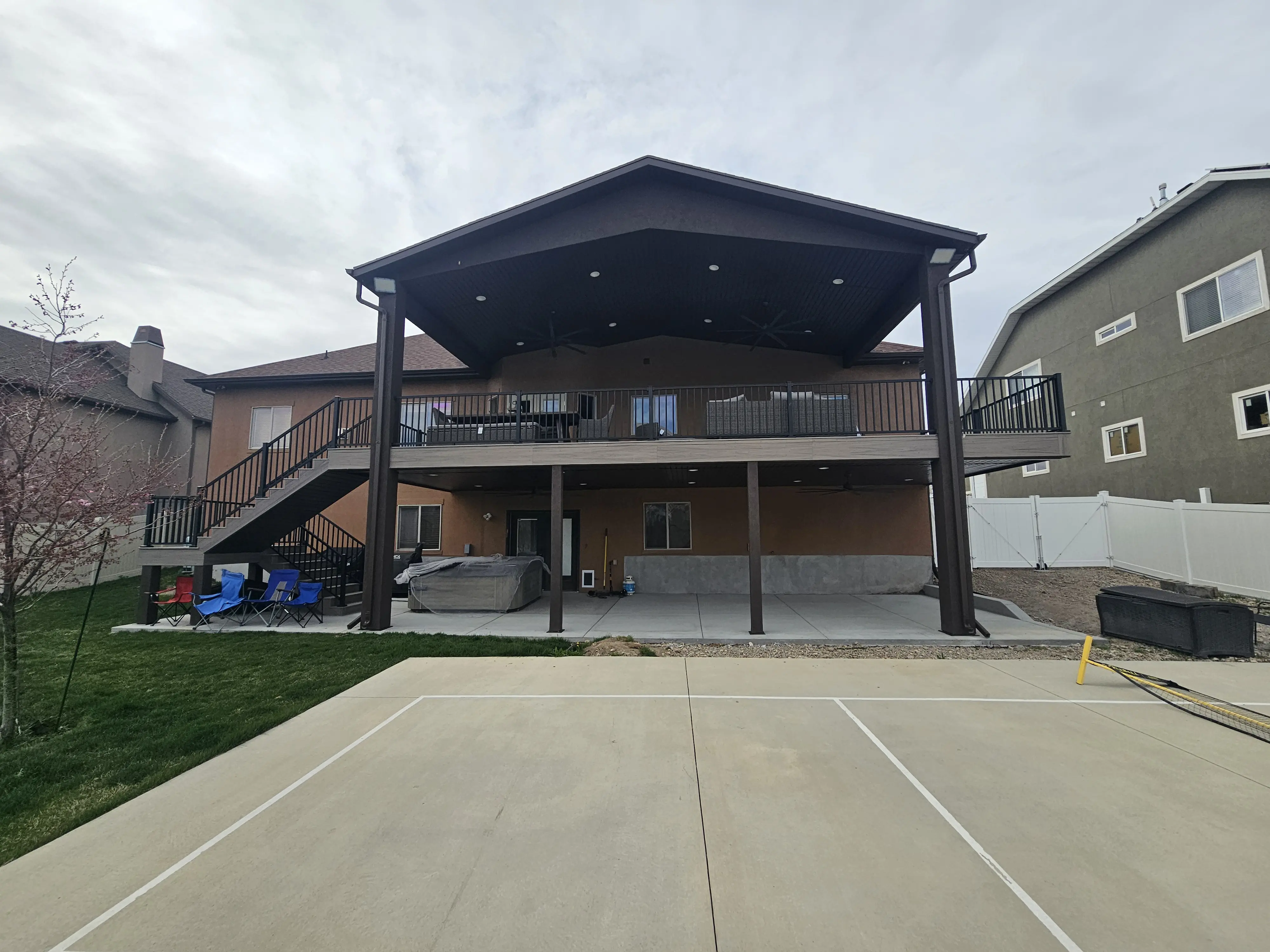 custom roof pic A two-story residential building with a covered porch and balcony. The porch is supported by black metal columns and has a black metal roof.