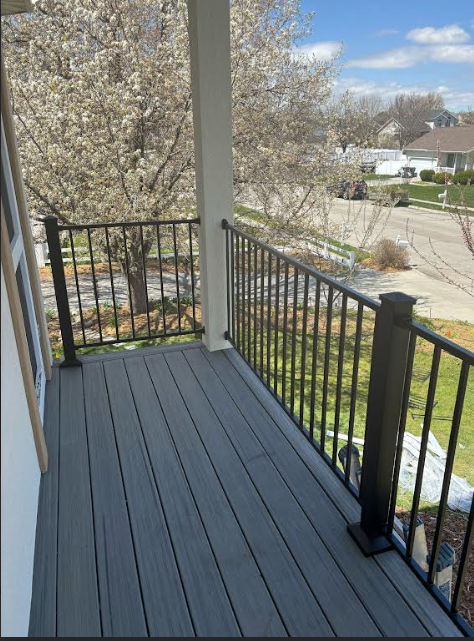 A porch overlooking a yard with blooming cherry blossom trees in the springtime.