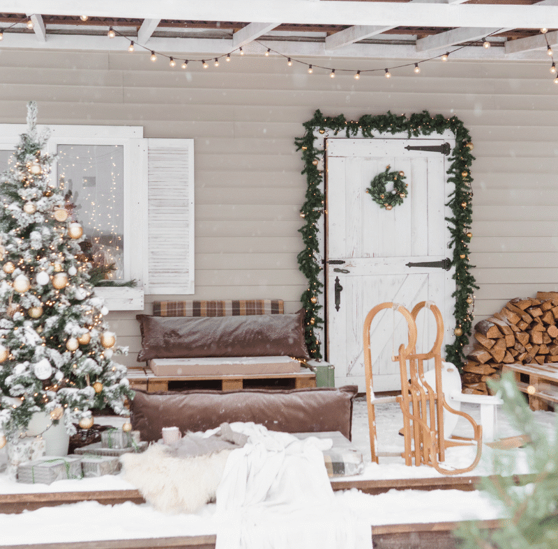 back porch deck area decorated for the holidays with a christmas tree and festive decorations