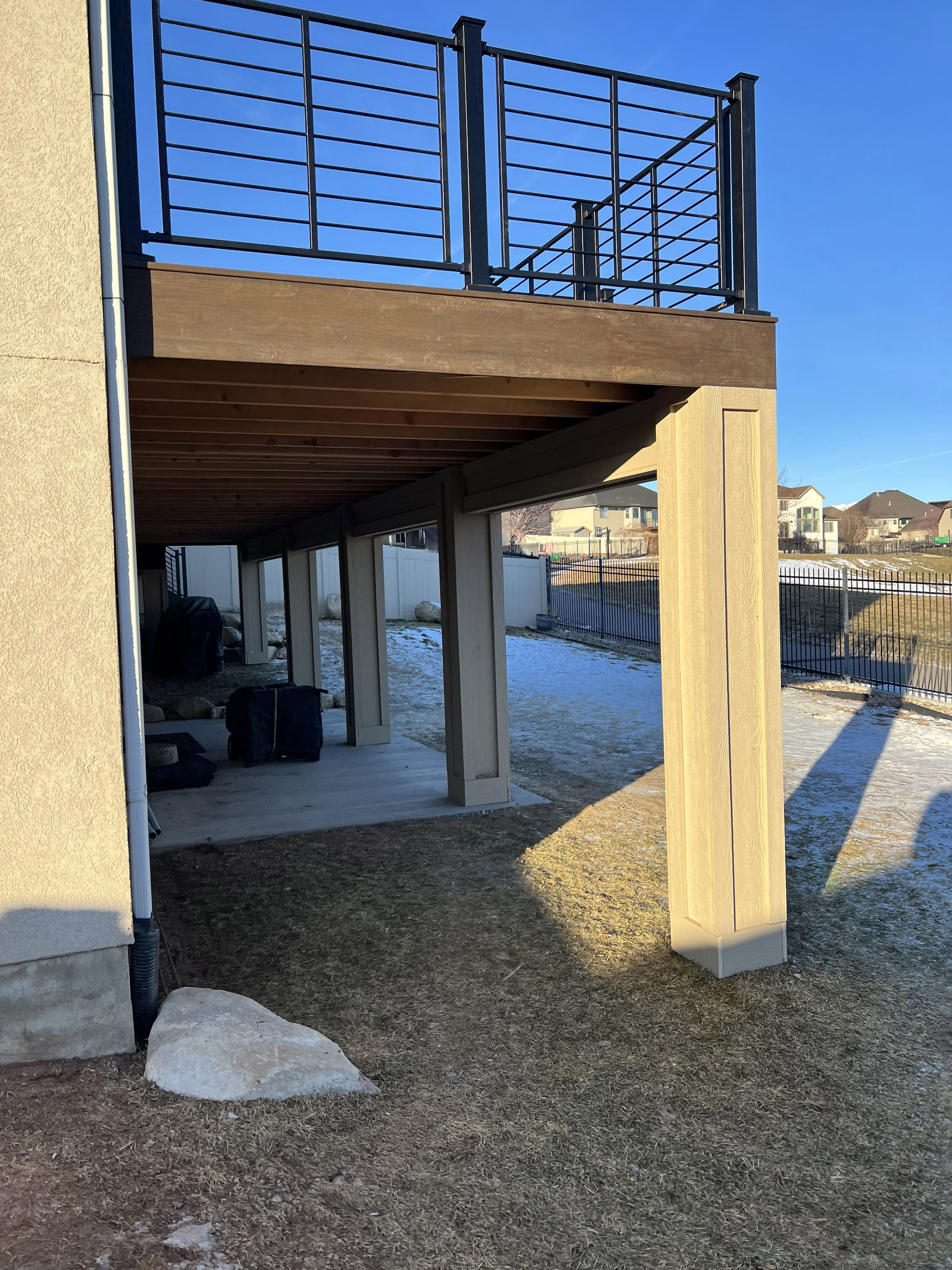 Horizontal-Railing-black-1-2-10 A covered outdoor patio or entryway with a metal railing system and a clear view of the surrounding yard