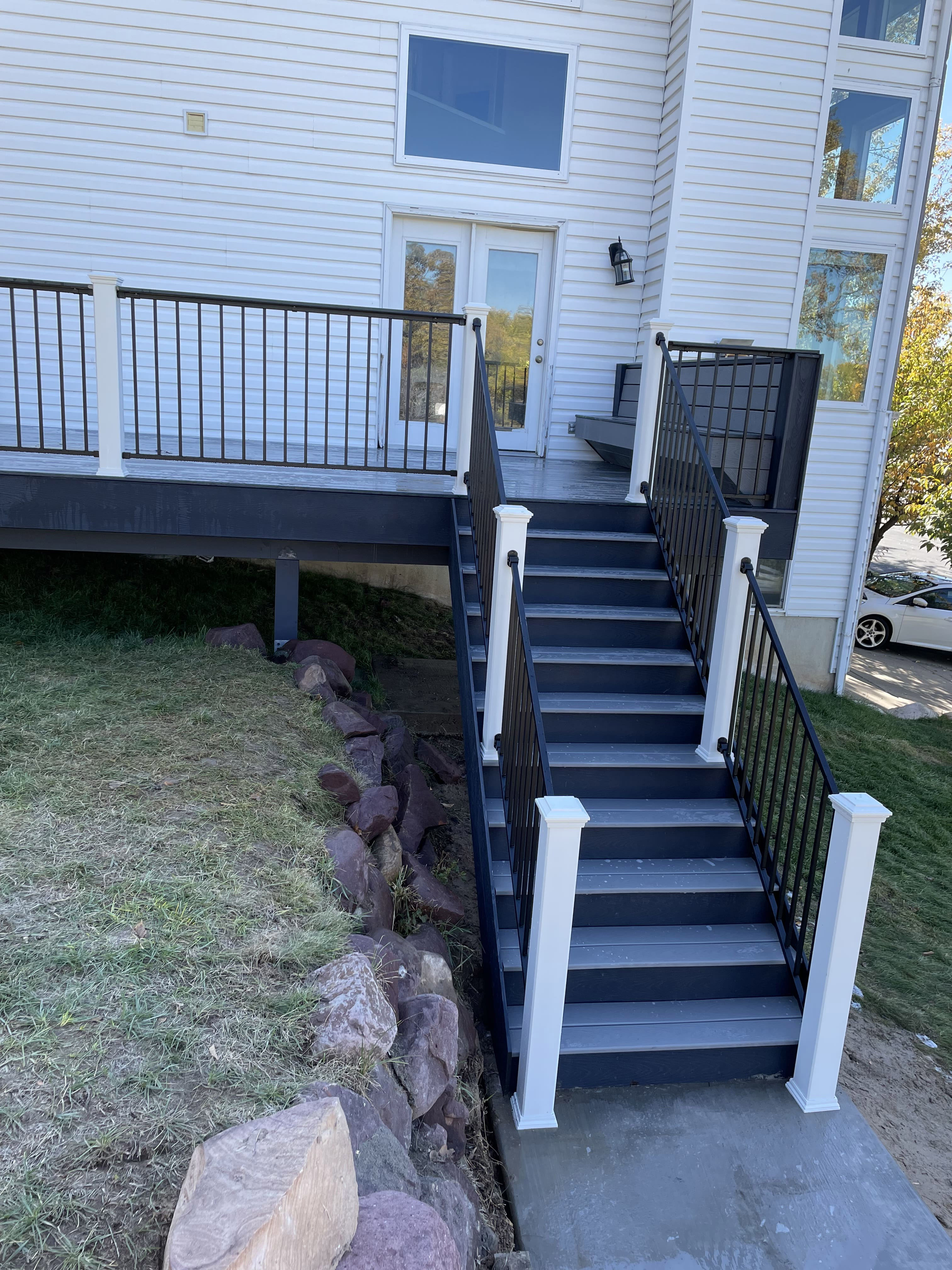black-cinch-railing-with-trex-transcend-posts-6 A closer view of the wooden staircase and deck, with the metal railings and a grassy yard visible