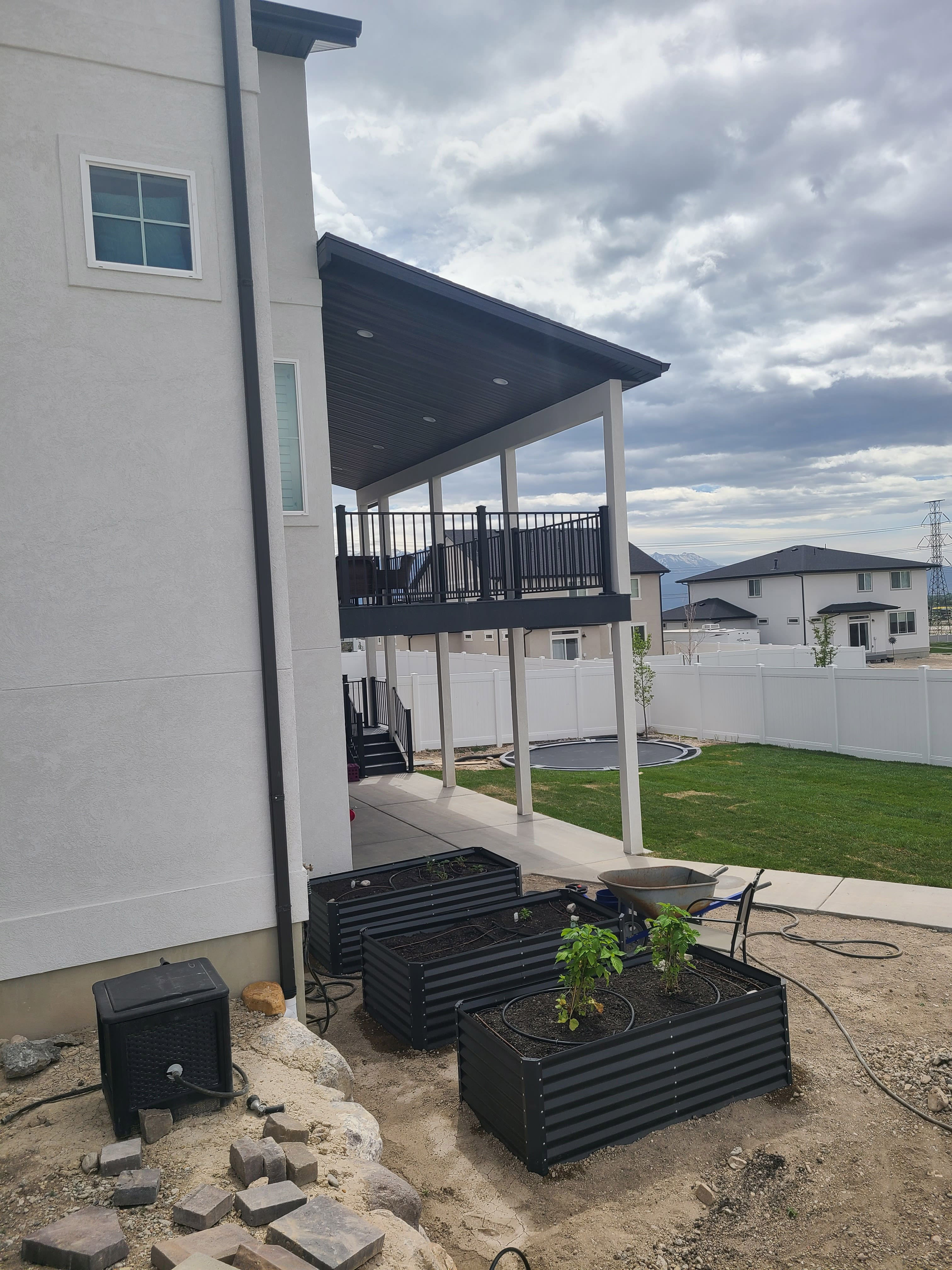 custom-roof-1-10 A modern, two-story house with a covered porch and balcony. The house has white siding and a gray roof, and there is a yard with some landscaping in the foreground.